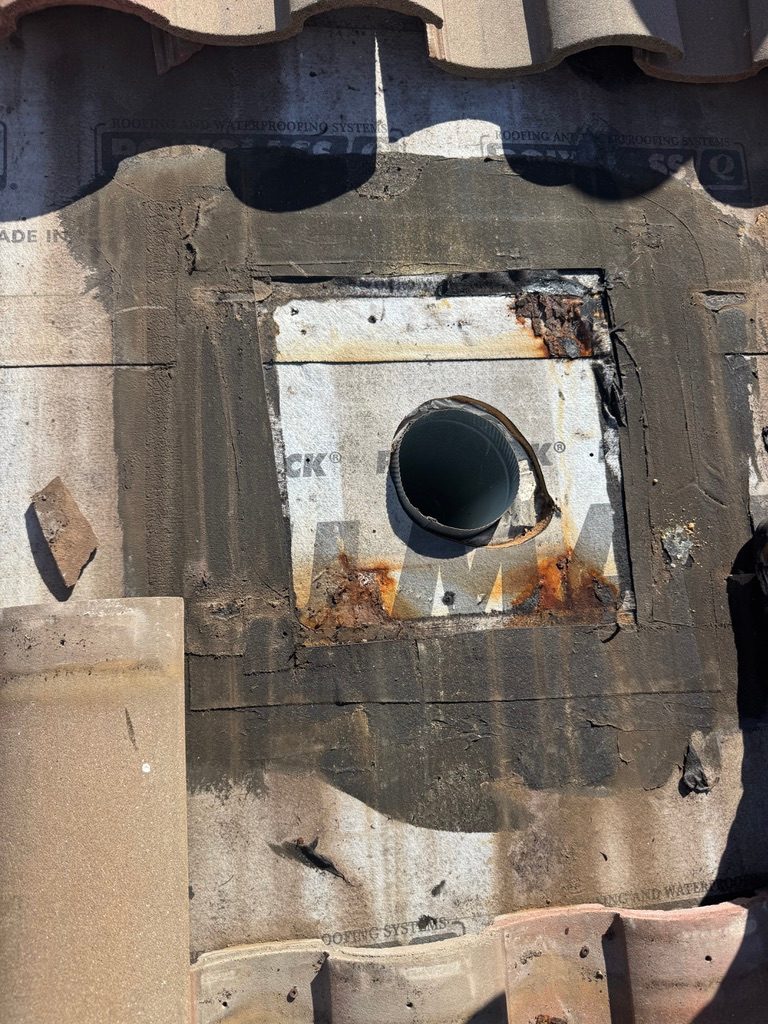 Roof vent opening with rusted flashing after the old gooseneck vent was removed, Naples tile roof